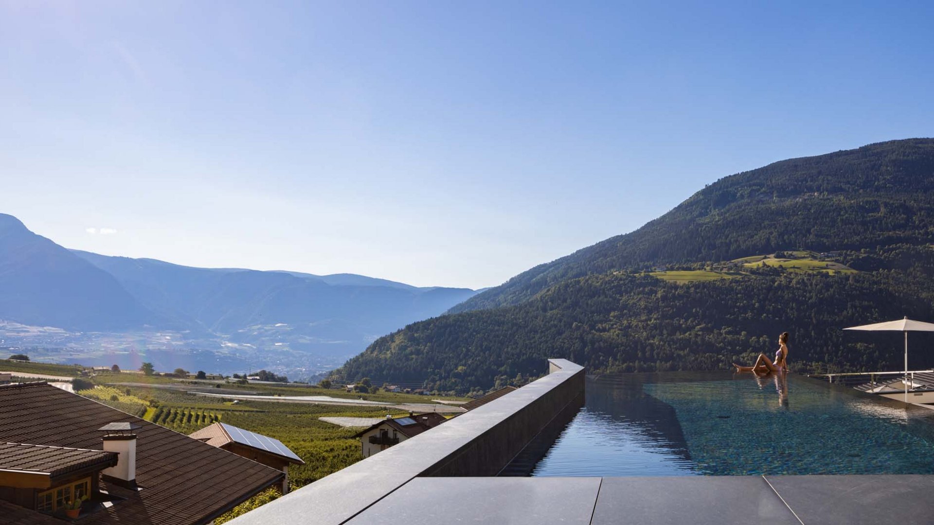 Donna rilassata al bordo di una piscina a sfioro con vista sulle montagne
